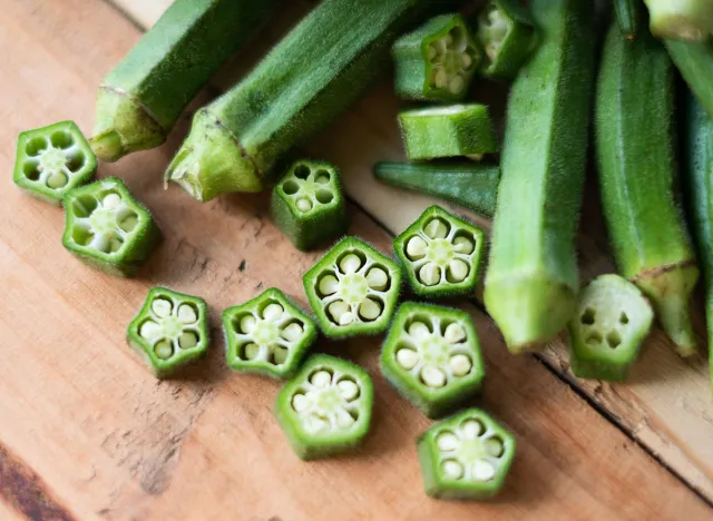 Farm fresh raw okra slices on wooden rustic aged chopping board. Close up of Lady Fingers or Okra over wooden background.