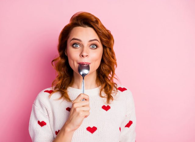 Close-up portrait of her she nice attractive pretty cute glad cheerful cheery wavy-haired girl licking spoon celebratory festal lunch homemade breakfast isolated on pink pastel color background
