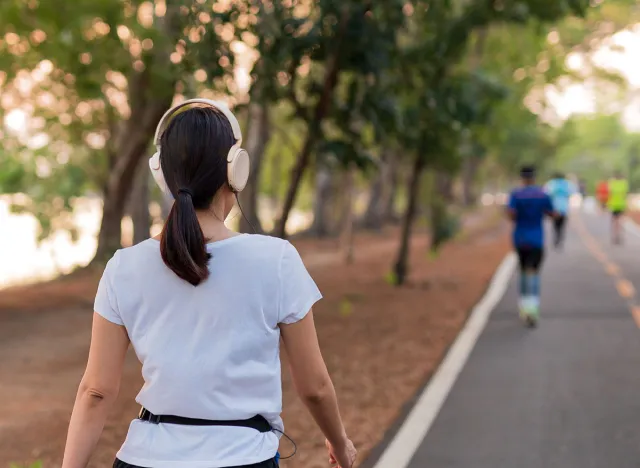 Woman exercise walking in the park listening to music with headphone