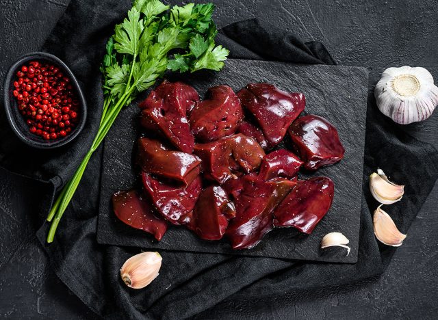 Raw chicken liver on a stone Board. Black background. Top view