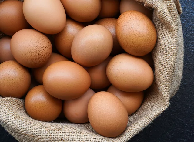 Chicken eggs in sack bag on black background.