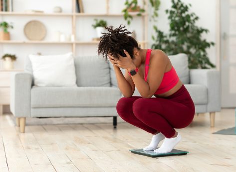 Weight Gain. Desperate Black Girl Crying Standing On Weight-Scales Slimming, Not Losing Weight On A Diet At Home. Copy Space