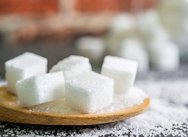 sugar cubes on black backround. Sugar is unhealthy nutrition and leads to obesity, diabetes, dental care