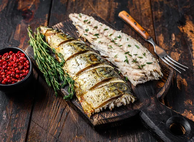 Roasted fillets of mackerel fish on cutting board. Dark wooden background. Top view.