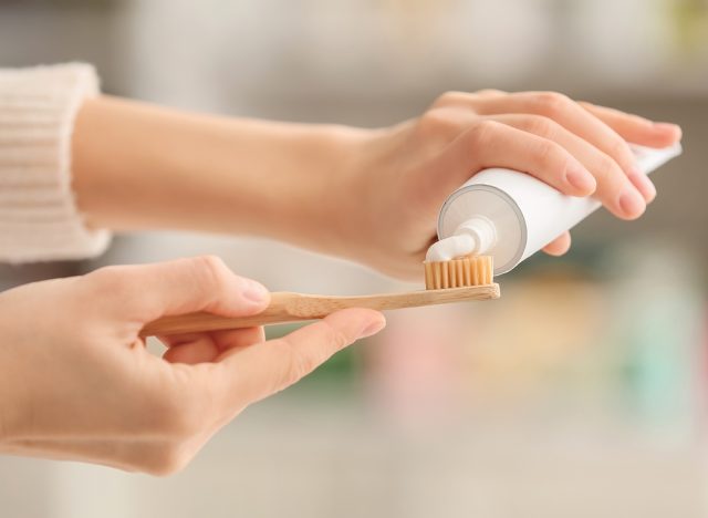 Female hands with tooth brush and paste on blurred background