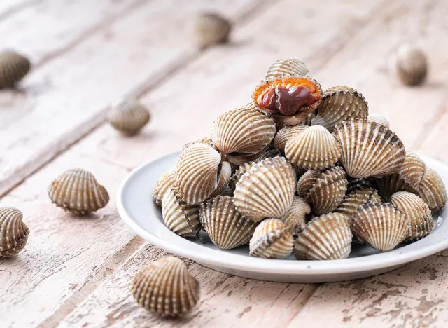fresh steamed cockles, boiled cockles in ceramic plate on old white wood texture background, easy seafood recipe menu, blood cockle