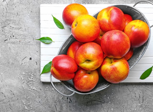 Sweet ripe nectarines in basket on grey background