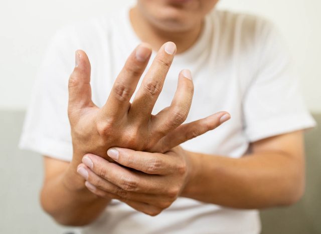 Close up,asian middle-aged man with shaking of Parkinson's disease,symptom of resting tremor,male patient holding her hand to control hands tremor,neurological disorders,brain problems,health care