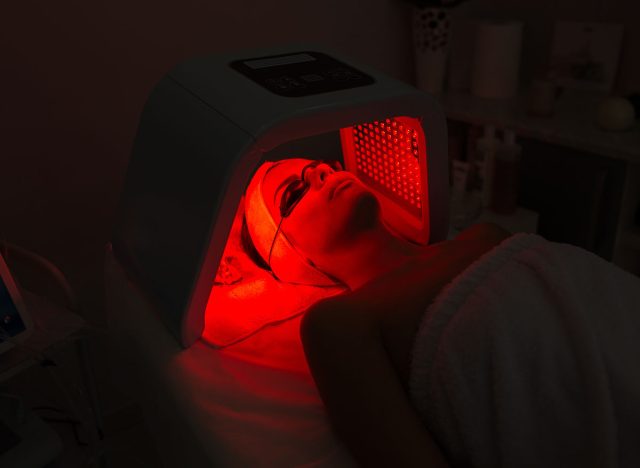 Woman having Ultraviolet LED light facial treatment at beauty salon. Cosmetology. female Face At Red Light Treatment At Beauty Clinic.
