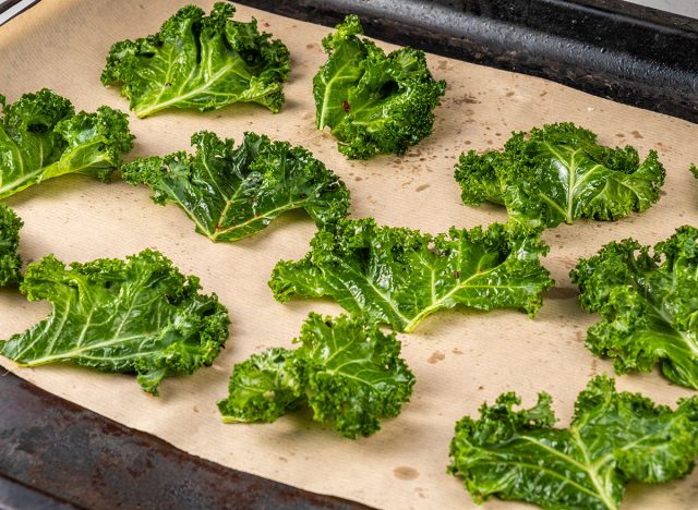 Kale chips on a baking sheet on parchment.