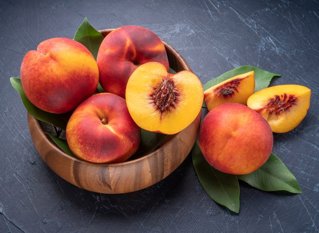 Yellow Peach with slice in wooden basket, Fresh Yellow Peach fruit in wooden bowl on wooden background.