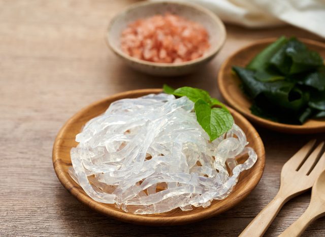 clear kelp or seaweed noodles in a wooden plate and Himalayan salt on wooden background. glass noodle