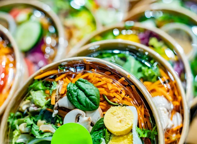 Pre-packaged vegetable salads displayed in a commercial refrigerator