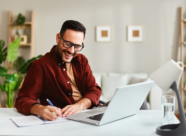 Young business man working at home with laptop and papers on desk