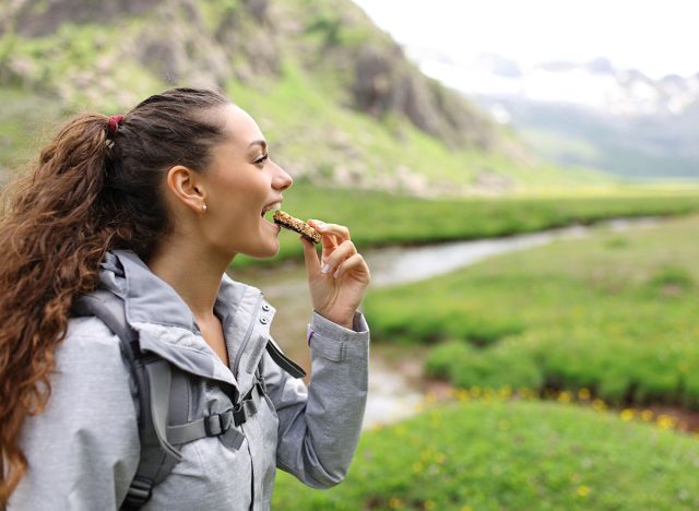 Profile of a hiker eating cereal bar in a valley in the mountain