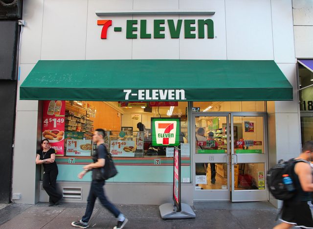 NEW YORK, USA - JULY 3, 2013: People walk past 7-Eleven convenience store in New York. 7-Eleven is world's largest operator, franchisor and licensor of convenience stores, with more than 46,000 shops.