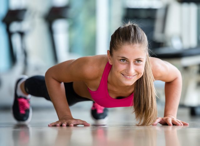 Gorgeous blonde woman warming up and doing some push ups a the gym