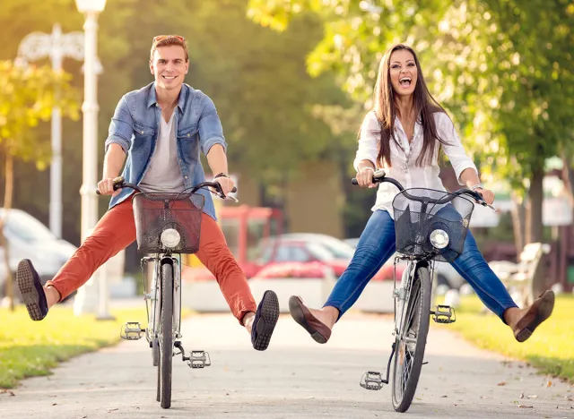 Happy funny young couple riding on bicycle
