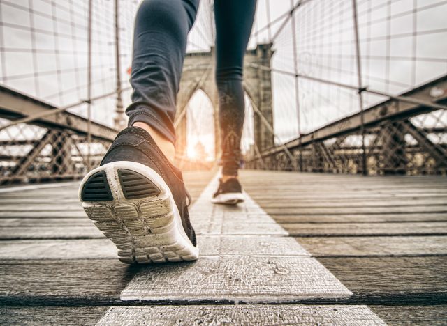 Woman running outdoors - Young sportive girl jogging at sunset on Brooklyn Bridge, close up on shoes