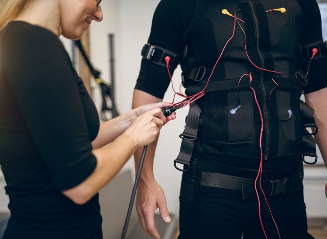 Female trainer connecting cables of ems suit