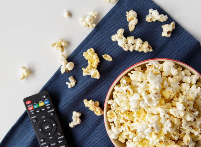 Popcorn with remote control on white table.