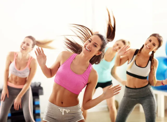 Group of happy people with coach dancing in gym