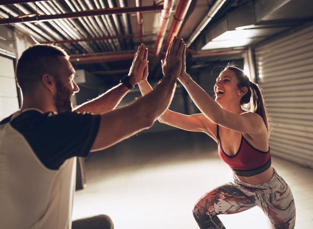 Young muscular smiling couple celebrating after successful hard workout at the garage.