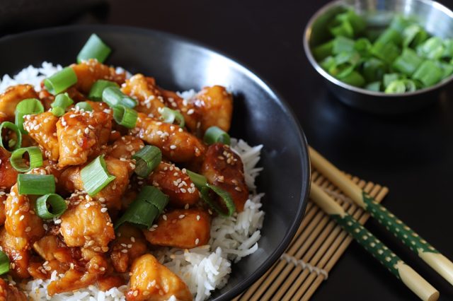 Crispy Sesame Chicken Asian Style, Sweet and sour fried chicken with steamed rice and spring onions