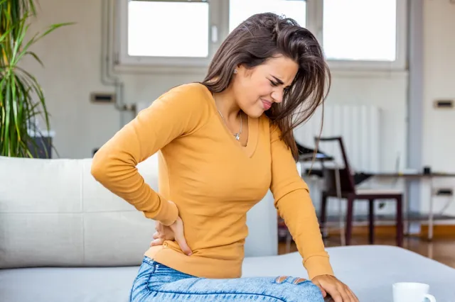 Young woman touching her kidney in pain.