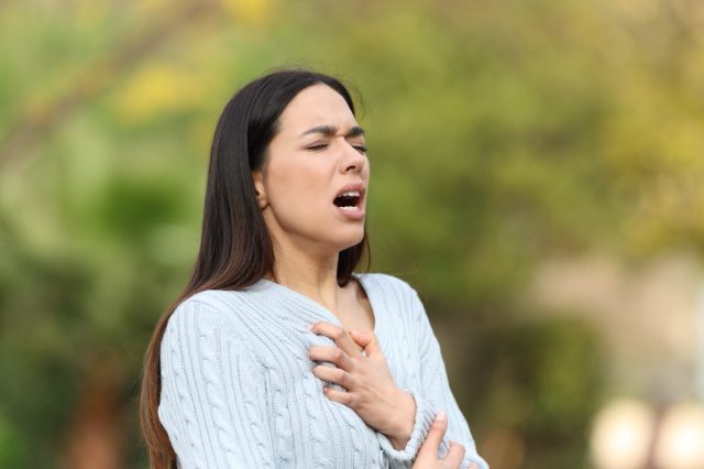 Stressed woman having breath problems walking in a park.