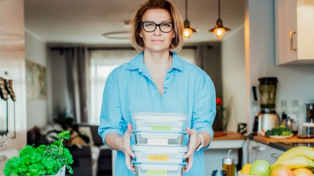 Healthy diet plan for weight loss, daily ready meal menu. Woman holding lunch boxes just cooked in advance, ready to be served. Containers with eco healthy food. Pre-cooking concept. Selective focus.