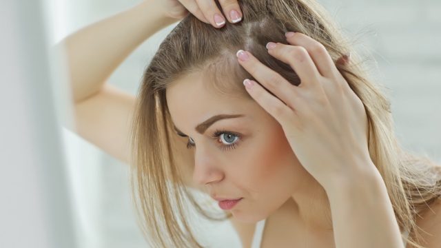 Woman looking in the mirror and checking her hair.