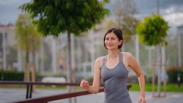 outdoor sports, workout and wellness concept. asian young strong, confident woman in sportive clothes in green park.