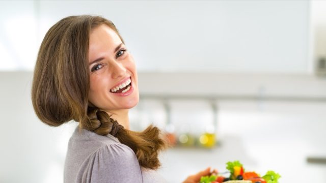Portrait of happy young housewife with greek salad.