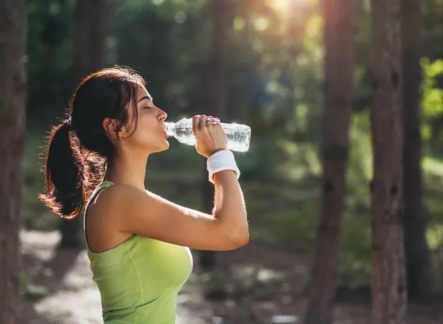 Girl drinking water from bottle in forrest