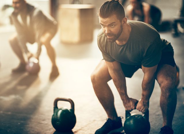 Fit young man in sportswear focused on lifting a dumbbell during an exercise class in a gym