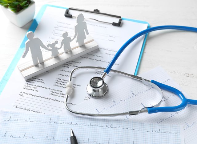 Composition with family figure and stethoscope on wooden table. Health care concept