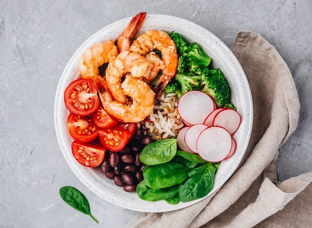 Healthy lunch. Shrimp Burrito Bowl with brown rice, spinach, radish, black beans, tomato and broccoli.