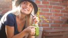 Blond young woman enjoying her green smoothie drink outside on terrace at sunset.