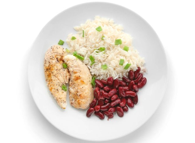 Delicious boiled rice with meat and beans on white background