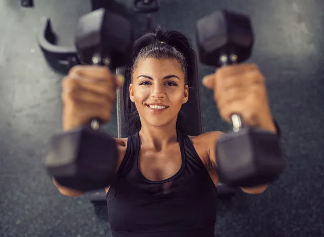 Concentrated woman lifting dumbbells in gym