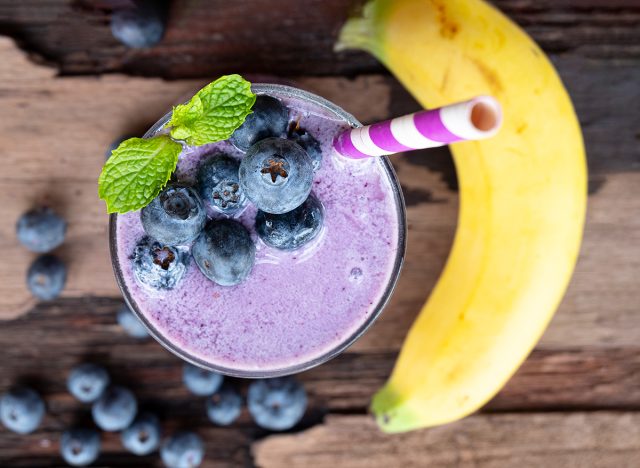 Blueberry mix banana smoothie purple colorful fruit juice milkshake blend beverage healthy high protein the taste yummy In glass,drink episode morning on a wooden background from top view.