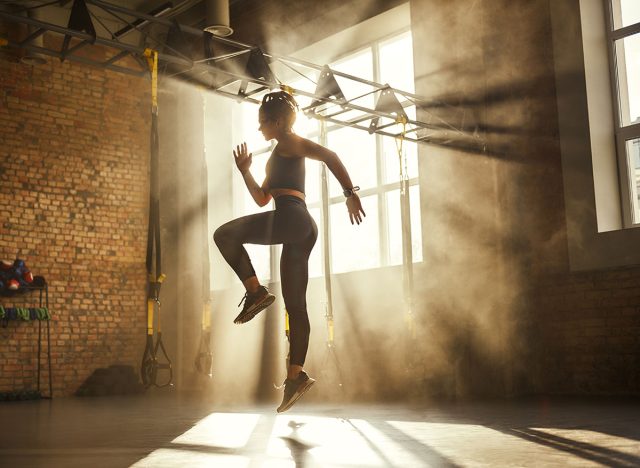 Always in good shape Full length of athletic woman in black sport clothing exercising in professional gym.