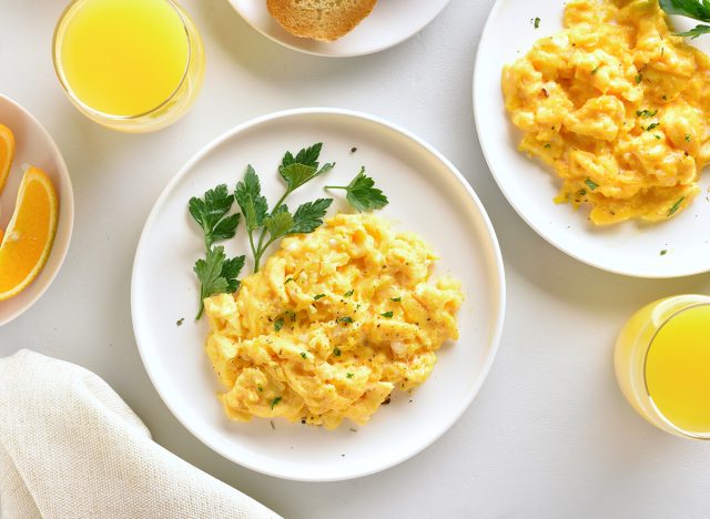 Healthy diet breakfast concept. Scrambled eggs and orange juice over white stone background. Top view, flat lay