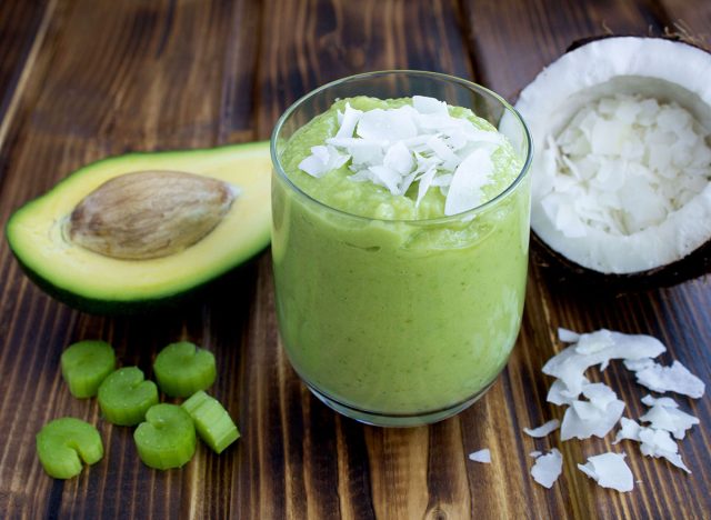 Smoothies with avocado, coconut milk and celery on the brown wooden background