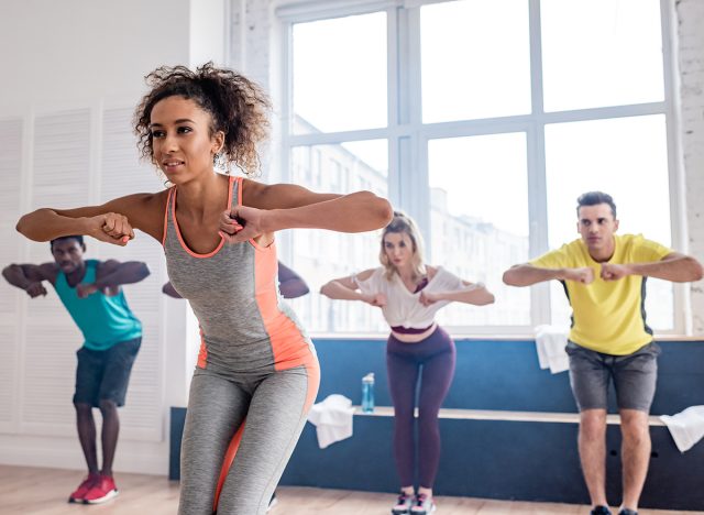 Selective focus of african american trainer leaning with multiethnic dancers movements of zumba in dance studio