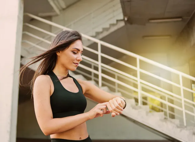 Attractive sport woman in sportswear use smart watch outdoors at urban environment