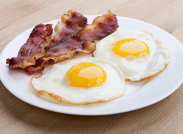 Plate with fried eggs, bacon isolated on white background