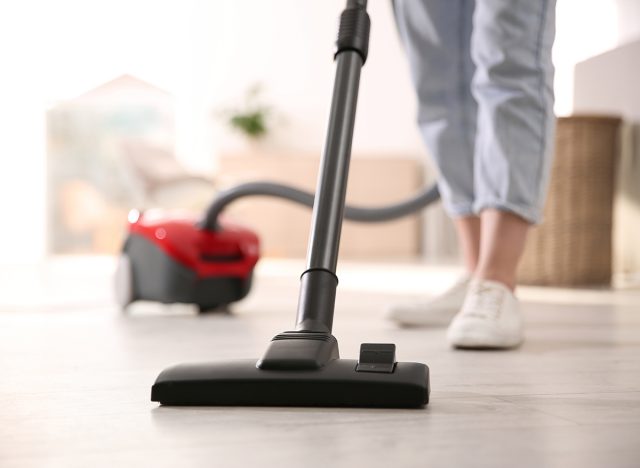 Young woman using vacuum cleaner at home, closeup