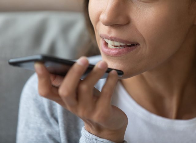 Close up woman recording voice message, speaking, young female holding phone in hand near face, chatting with friends online or speakerphone, activating digital assistant on smartphone